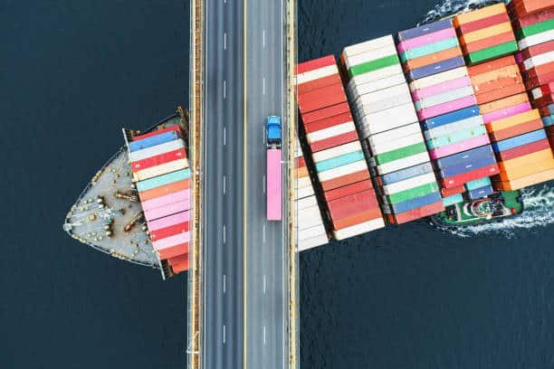 Container ship passing under bridge with truck above — China to Argentina freight route