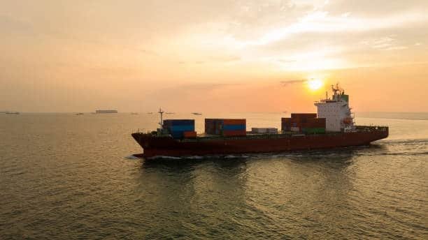 Fully loaded container ship at sea during golden hour, illustrating international shipping leading to inland drayage.