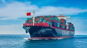 Container ship flying Chinese flag, transporting goods from China to Bahrain across the sea.