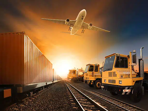 Airplane flying over container train and yellow cargo trucks at sunrise representing fast logistics to Cameroon