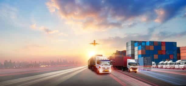 Fleet of container trucks at sunset with airplane above, indicating land and air logistics