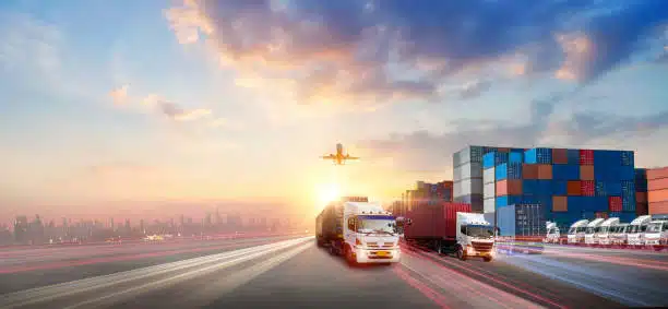 Fleet of container trucks at sunset with airplane above, indicating land and air logistics