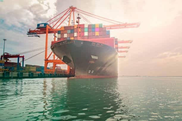 Container ship being loaded with export cargo at sunrise