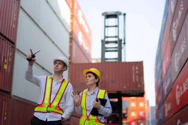 Logistics team coordinating shipments in container yard for door-to-door transport