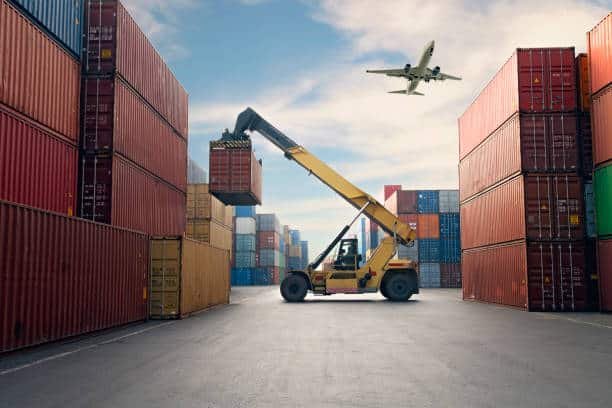Forklift handling cargo in a container yard with airplane above, illustrating multimodal logistics