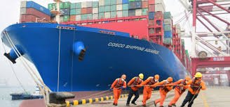 Dock workers securing large COSCO container vessel for shipping from China to the Philippines.