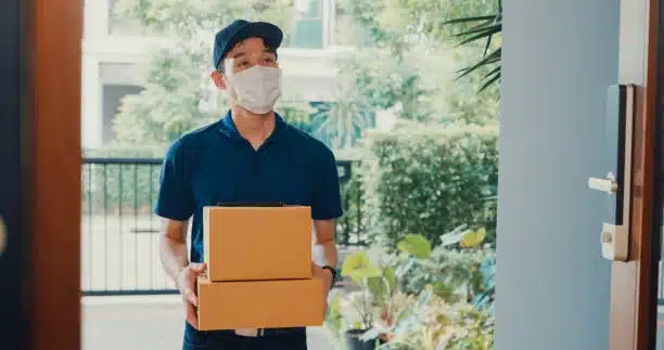 Courier wearing mask delivering packages in contactless door-to-door service