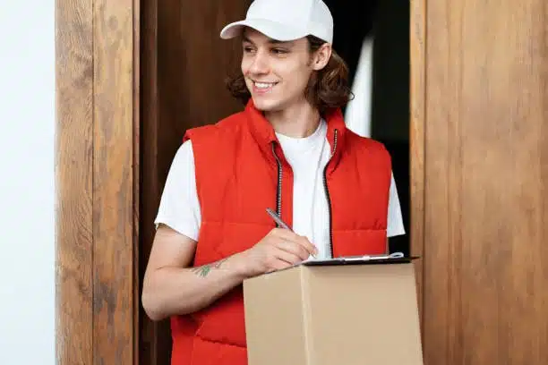 Smiling recipient signing for a DDP-delivered package at the door