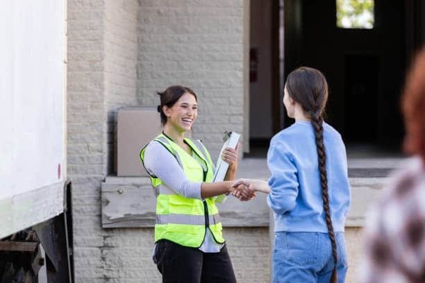 Female delivery staff shaking hands with customer at loading dock