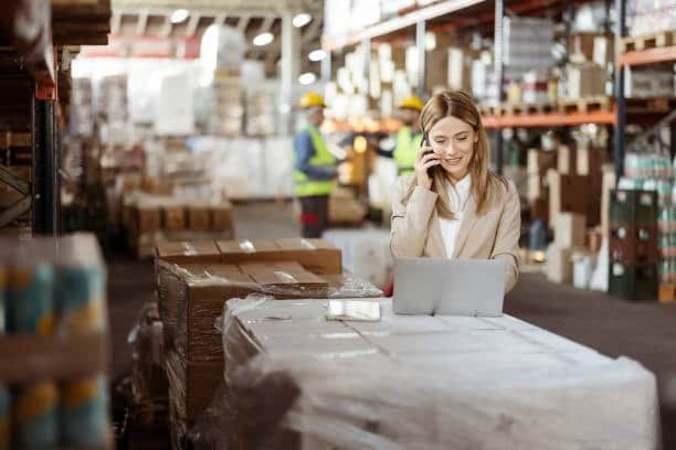 Woman coordinating inventory and orders via laptop in a warehouse environment
