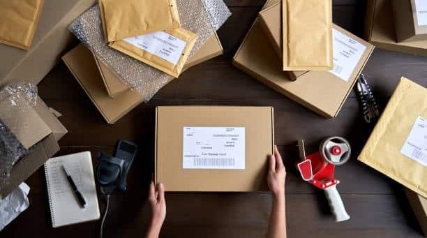 Top-down view of packaging station with labeled parcels, envelopes, and shipping tools