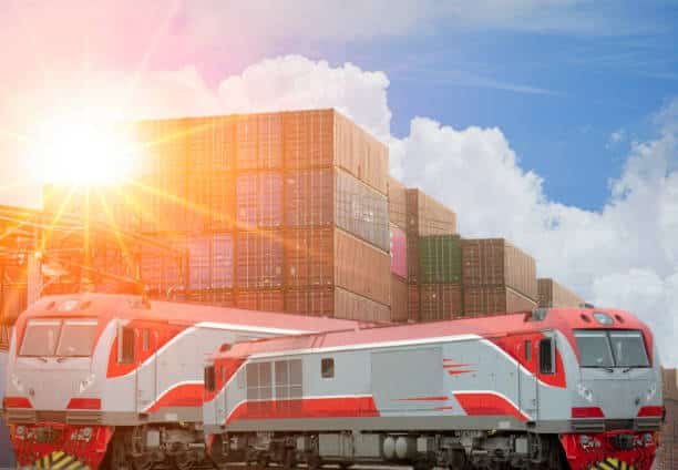 Red locomotives and stacked containers at a shipping yard transporting freight to the UK