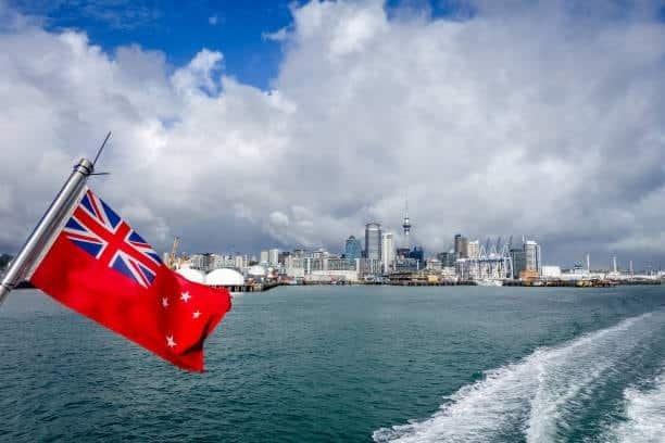 View of Auckland harbor from sea with New Zealand flag in foreground