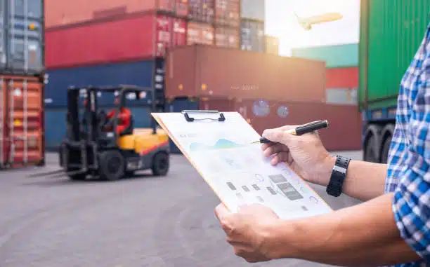 A logistics worker checking export documents at a port container yard