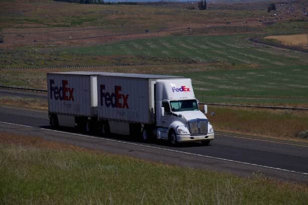 FedEx LTL truck with double trailers moving on the road under open sky