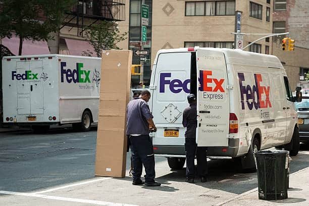 FedEx workers loading packages into vans, comparing SmartPost and Express services