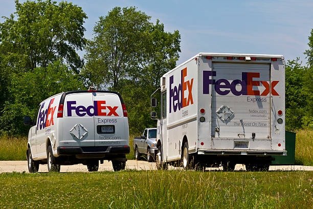 Two FedEx Express vehicles parked near a grassy area, representing different delivery methods