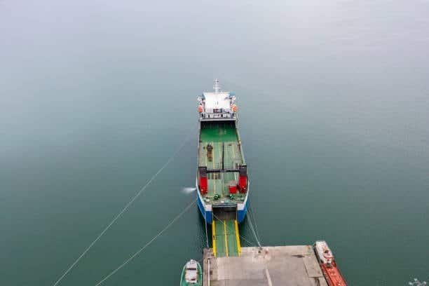 Aerial shot of a Ro-Ro cargo vessel docked at the port for vehicle transpo
