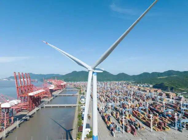 Aerial view of a container terminal in China with wind turbine, symbolizing eco-friendly shipping practices