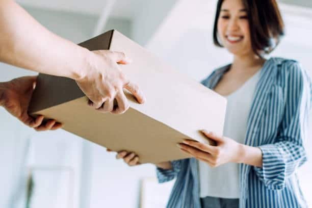 Customer receiving parcel directly from courier in door-to-door service