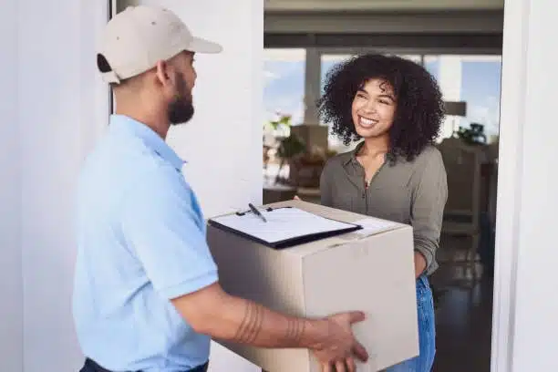 Smiling woman accepting a package through home delivery door-to-door service