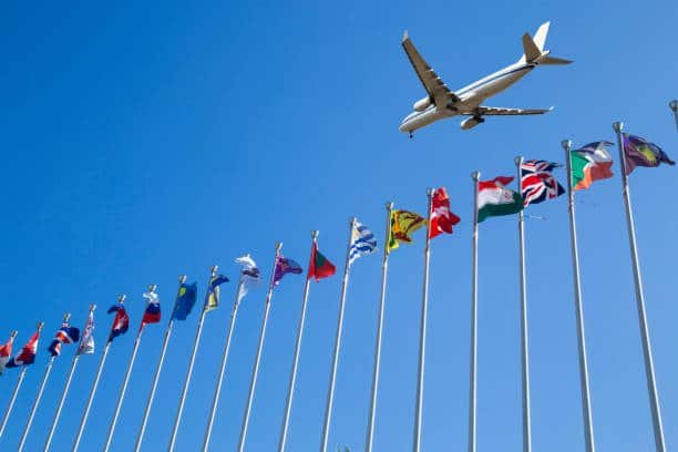 Plane flying over international flags, representing global trade routes including China to Algeria logistics