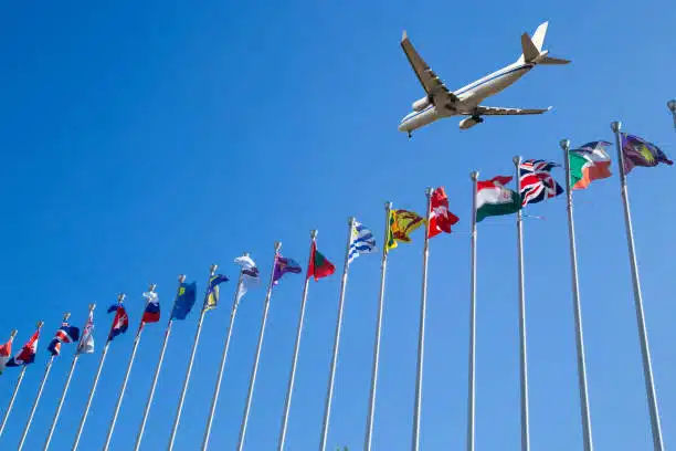 Plane flying over international flags, representing global trade routes including China to Algeria logistics
