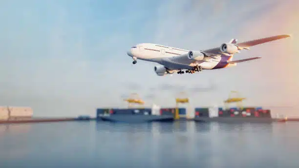Airplane approaching port with container ships in background, illustrating air-sea logistics from China to India