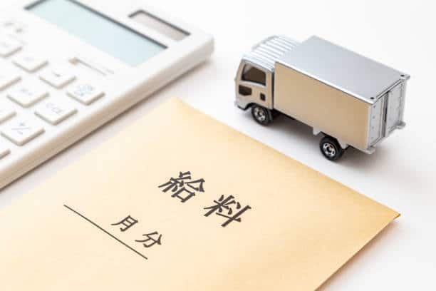 Japanese envelope labeled with shipping terms next to a calculator and toy truck