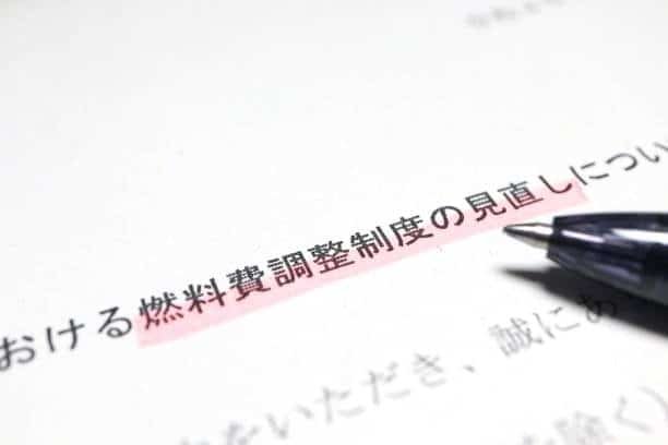 Japanese document highlighting fuel cost adjustment terms with a pen