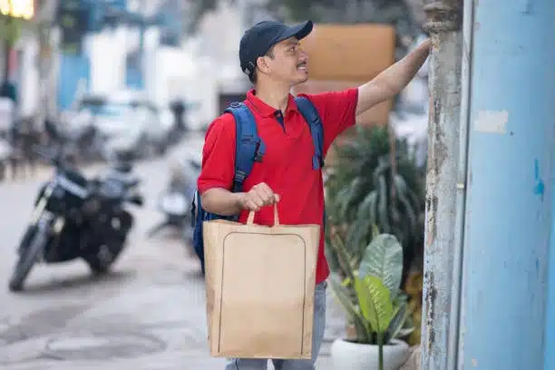 Local courier delivering a package to residential door as part of door-to-door logistics