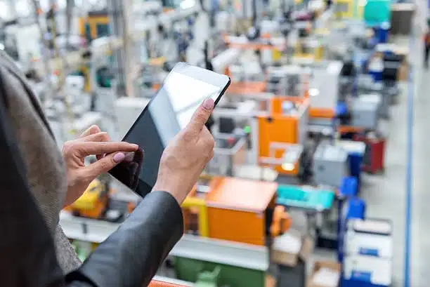 Woman managing logistics planning with tablet inside a production facility