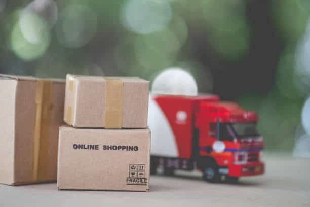 Cardboard box labeled “Online Shopping” with a toy truck in the background, symbolizing small-load shipping