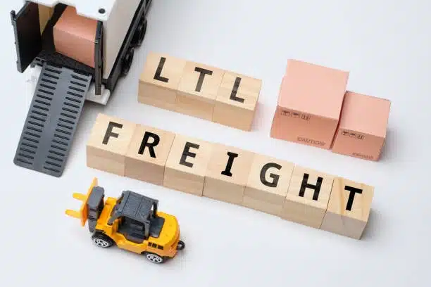Toy model of forklift, boxes, and wood blocks spelling out “LTL Freight” on a white background