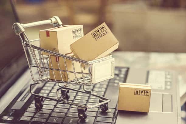 Small shopping cart with fragile shipping boxes placed on a laptop keyboard