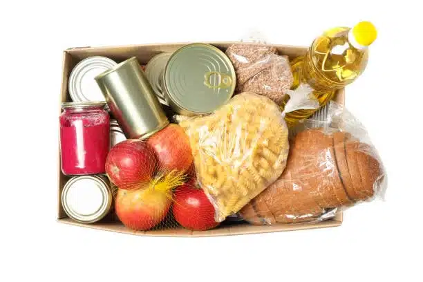 Cardboard box with canned goods, pasta, and fresh produce ready for shipment.