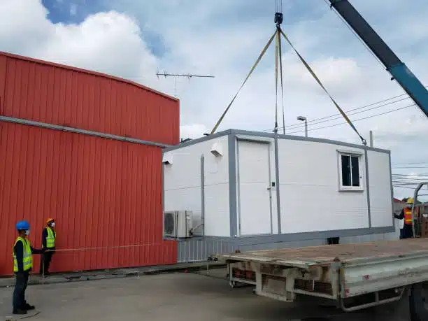 Crane loading a prefabricated structure onto a trailer for international shipping