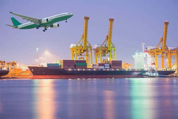 Container terminal with airplane flying overhead, symbolizing nighttime freight from China to Hungary.