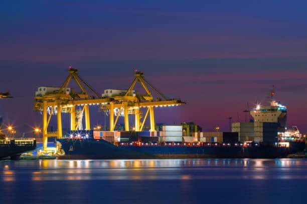 Cargo ship being loaded at night, representing ocean freight from China to Egypt.