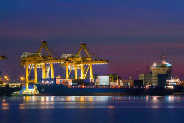 Cargo ship being loaded at night, representing ocean freight from China to Egypt.