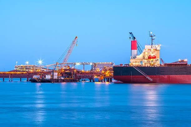 Shipping terminal at night with cargo vessel docked for loading