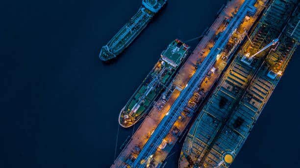 Aerial night view of cargo ships docked at a busy shipping terminal