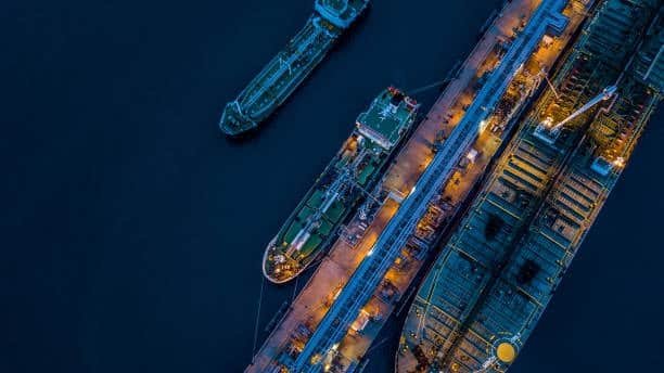 Aerial view of large ocean freight tankers docked at port under night lighting, showcasing global maritime logistics operations