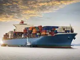 Cargo ship carrying containers under a sunset sky, symbolizing ocean freight to Bahrain.