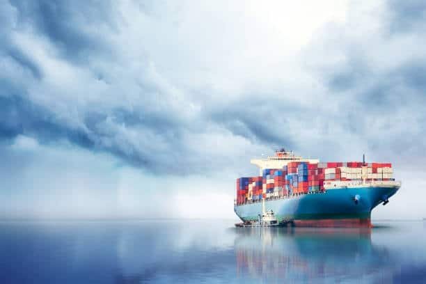 Large ocean shipping container vessel at sea under dramatic cloudy sky