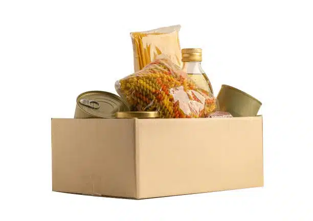 Box with essential pantry items like oil, pasta, and canned food prepared for safe food delivery.