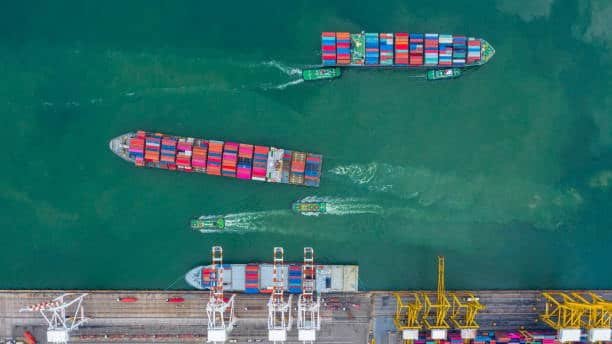 Heavy cranes operating at port to unload colorful containers from a vessel in Singapore