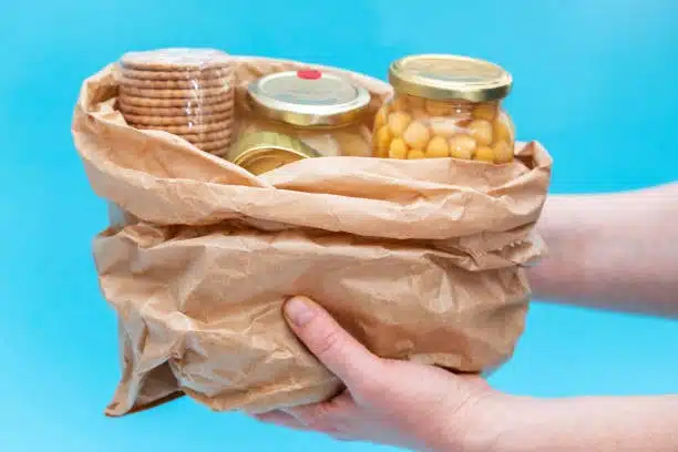 Canned and preserved perishable food in jars and plastic wrap inside a paper bag for short-distance delivery.