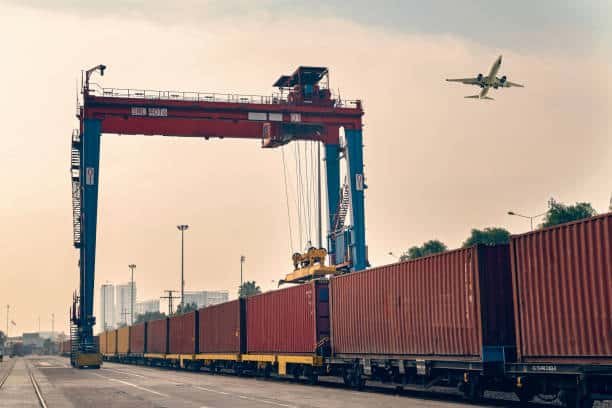 Cargo containers being loaded onto a freight train for rail shipping from China to Spain.