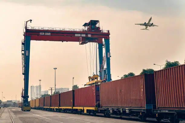 Cargo containers being loaded onto a freight train for rail shipping from China to Spain.